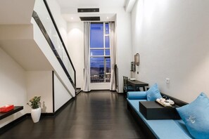 Un intérieur moderne avec un escalier, un canapé avec des coussins, une petite table et une plante en pot.