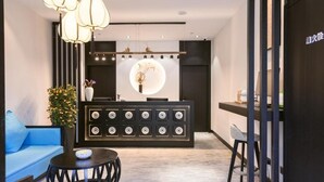 A modern reception area with a central desk, a blue sofa, and a decorative plant. - Gongxili - Yuejian Hotel (Kunming)
