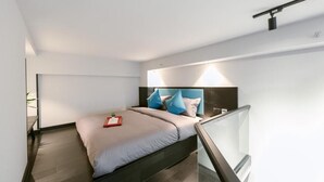 A modern bedroom with a bed, a nightstand, a bedside table, and a glass railing. - Gongxili - Yuejian Hotel (Kunming)