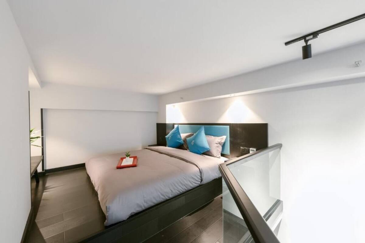 A modern bedroom with a bed, a nightstand, a bedside table, and a glass railing.