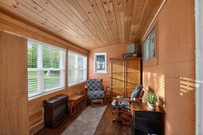 Ein gemütliches Blockhaus mit Holzwänden, Kamin, einer Couch, einem Sessel und einem kleinen Tisch.