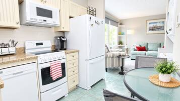 A modern kitchen with a microwave, stove, oven, and refrigerator. There is a dining area with a table and chairs.