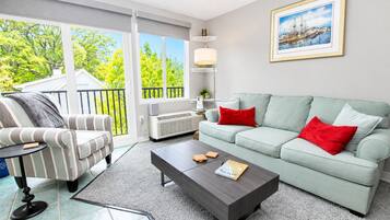 A living room with a striped sofa, a light green couch with red pillows, a dark coffee table, and a framed picture on the wall.