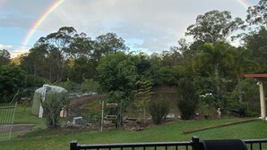A garden with a rainbow, trees, and a fenced area.
