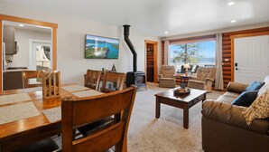 A cozy living room with a fireplace, dining area, and a view of the outdoors. - Hayden Lake Oasis | Private Dock and Boat Slip | Fire Pit and Lake Access (Hayden)