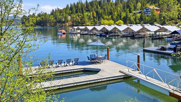 A marina with docked boats, a wooden pier, and a row of cabins with canopies. - Hayden Lake Oasis | Private Dock and Boat Slip | Fire Pit and Lake Access (Hayden)