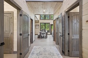 Un intérieur en bois avec un espace central dédié à la salle à manger, plusieurs portes et une vue sur l’extérieur.