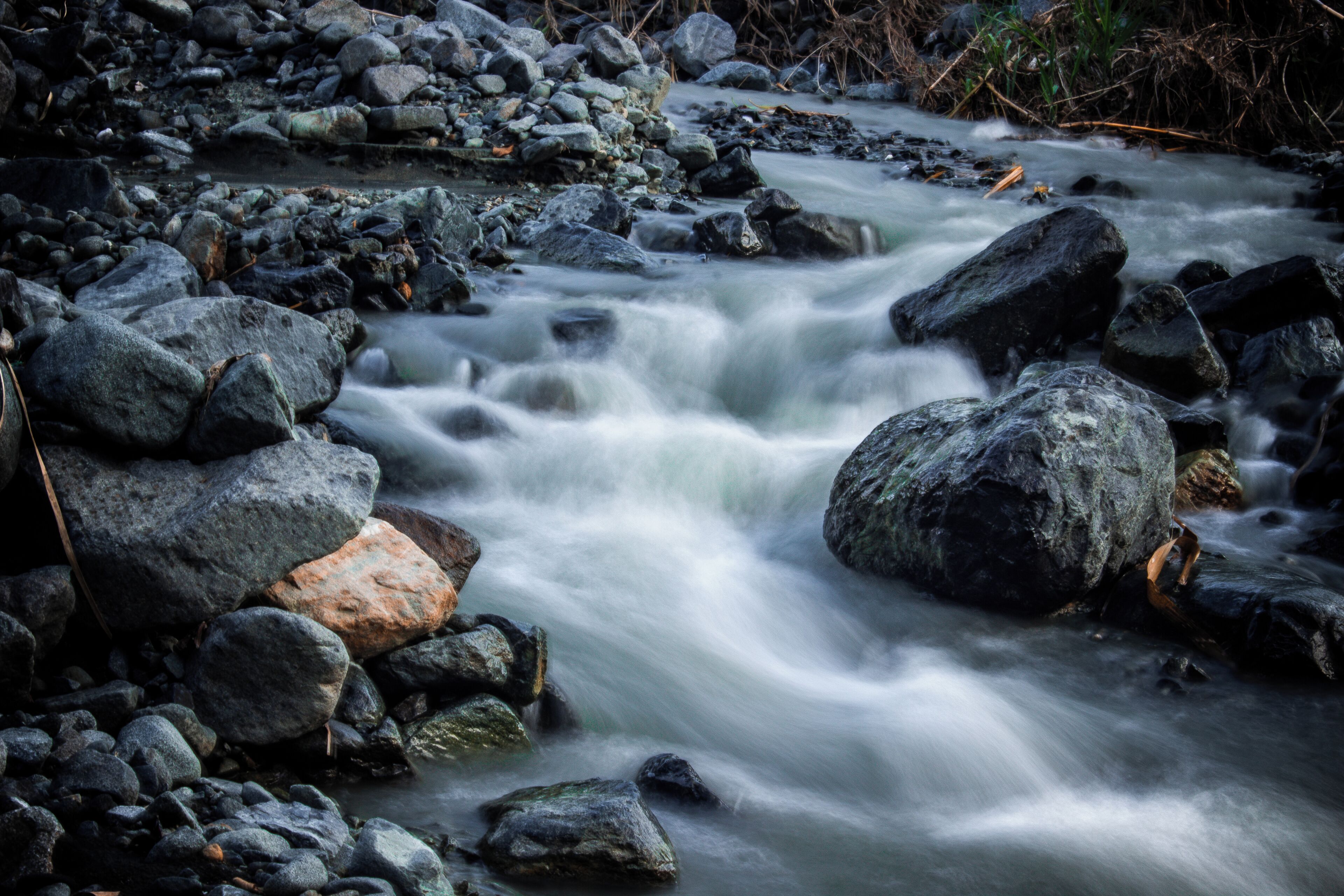 A river flowing through a rocky landscape with large boulders and a calm water surface.