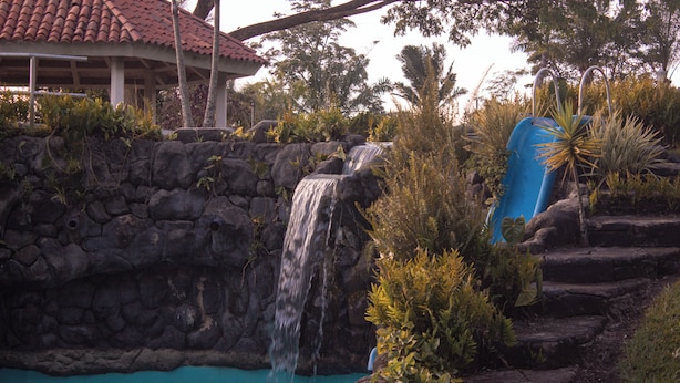 A waterfall, a pool, and a covered structure with steps. - Alma Terra Campestre (Ginebra)