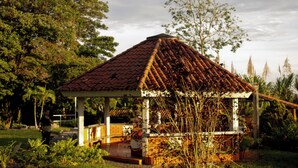 A gazebo with a tiled roof, surrounded by greenery and trees. - Alma Terra Campestre (Ginebra)