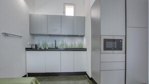 A compact kitchen with a microwave, cabinets, and a small window. - 1 bedroom nice apartment in Genova (Genova)