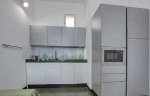 Eine kleine Küche mit Mikrowelle, Schränken und einem kleinen Fenster.
