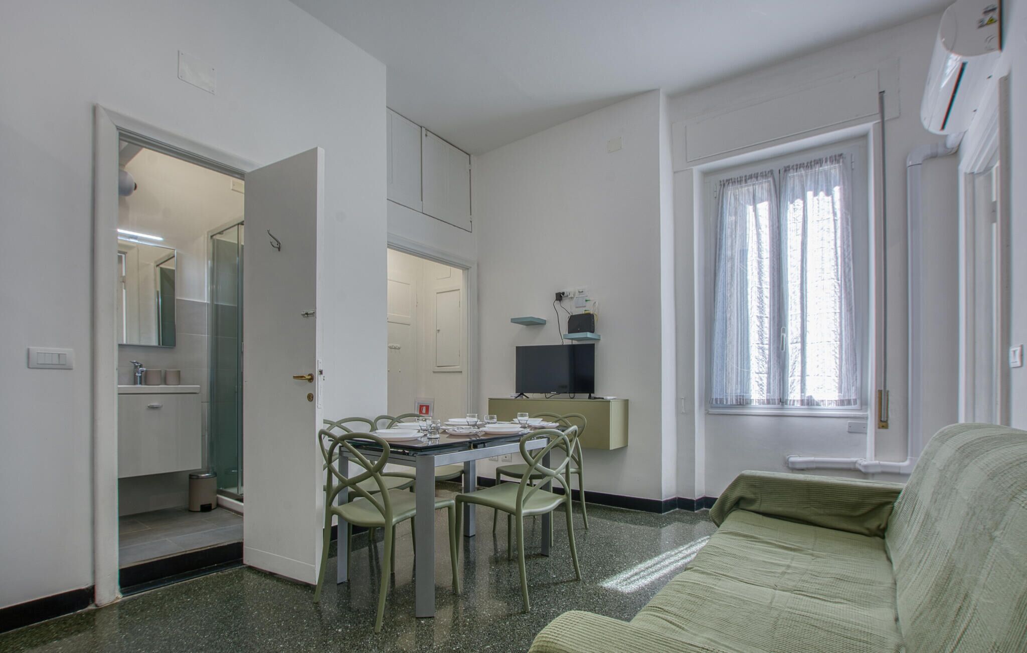 Un espacio habitable compacto con comedor, kitchenette y ventana con cortinas.