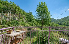 A balcony with a table and chairs, surrounded by a purple railing, overlooking a lush green valley with trees and a mountain in the distance. - 3 bedroom stunning home in Rezzoaglio (Rezzoaglio)