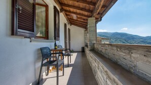 Ein Balkon mit Tisch, Stühlen, einer Flasche und einem Glas.