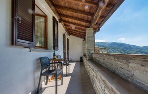A balcony with a table and chairs, a bottle, and a glass.