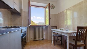 Eine Küche mit Fenster, Heizkörper, Herd und einem Esstisch mit Stühlen.
