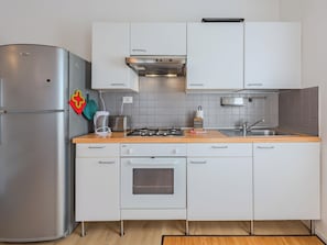 Eine moderne Küche mit einem Edelstahl-Kühlschrank, einem Gasherd, einem eingebauten Backofen und weißen Schränken.