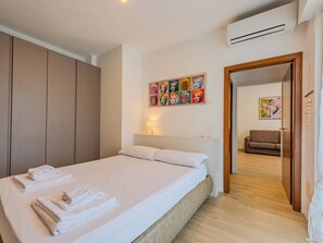 Ein Hotelzimmer mit Bett, Schrank, einem Bild an der Wand und einer Klimaanlage.