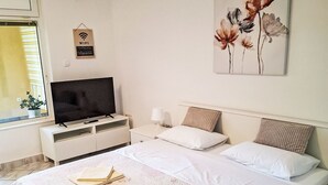 Ein Hotelzimmer mit Bett, Fernseher, Nachttisch, Lampe und einem Gemälde an der Wand.