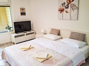 A hotel room with a bed, a TV, a bedside table, a lamp, and a painting on the wall. - Gemütliches Erdgeschoss-Studio für 2 Personen by Interhome (Crikvenica)