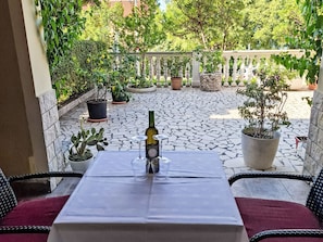A patio with a table set for two, potted plants, and a bottle of wine. - Gemütliches Erdgeschoss-Studio für 2 Personen by Interhome (Crikvenica)