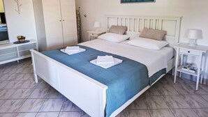 Quarto com cama, guarda-roupa, mesa de cabeceira, um quadro e espelho.