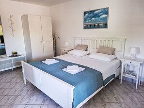 Ein Schlafzimmer mit Bett, Schrank, Nachttisch, einem Gemälde und einem Spiegel.