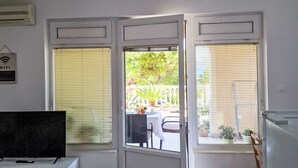 Quarto com televisão sobre suporte, porta que dá para o exterior e placa indicando disponibilidade de WiFi.