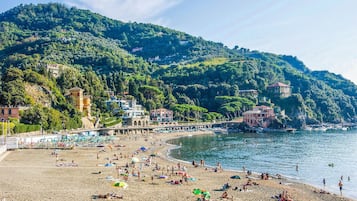 Una spiaggia con persone, un molo e edifici su una collina.