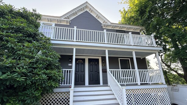 A two-story house with a front porch, a balcony, and a driveway.