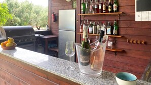 Un espace bar équipé d’un grill, d’un réfrigérateur et de différentes bouteilles d’alcool disposées sur des étagères.