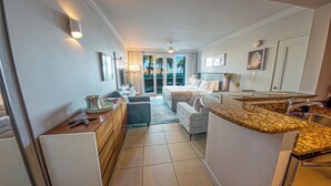A hotel room with a kitchenette, a bed, a seating area, and a view of the outdoors. - Coastal Summer Villa: Pool/Kitchen/Patio (San Juan)