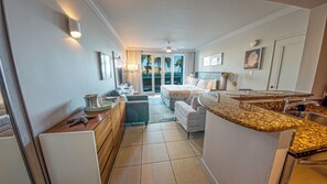 A hotel room with a kitchenette, a bed, a seating area, and a view of the outdoors. - Coastal Summer Villa: Pool/Kitchen/Patio (San Juan)