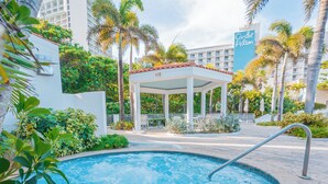 A hotel pool area with a hot tub, surrounded by palm trees and a covered seating area. - Coastal Summer Villa: Pool/Kitchen/Patio (San Juan)
