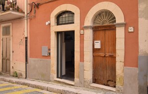 A building with a wooden door, a window with a metal grill, and a number plaque. - WHITE STONE HOUSE a Ragusa (Ragusa)