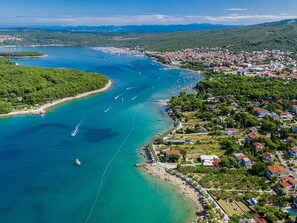 Luftaufnahme einer Küstenstadt mit einem Hafen, einem dicht besiedelten Wohngebiet und einem Strand.