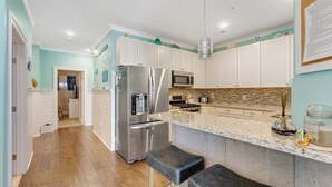 A modern kitchen with white cabinets, stainless steel appliances, and a granite countertop. - Residence 103N at The Sandcastle Condominiums (Wildwood Crest)