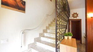 A staircase with a metal railing, a wooden door, and a wall-mounted ship's wheel.