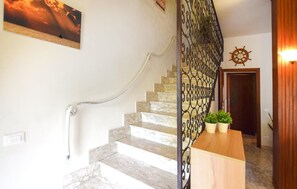 A staircase with a metal railing, a wooden door, and a wall-mounted ship's wheel.