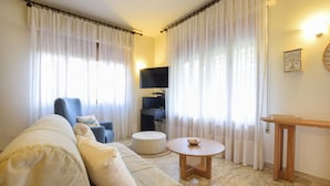 A living room with a sofa, a round table, a chair, and a television.