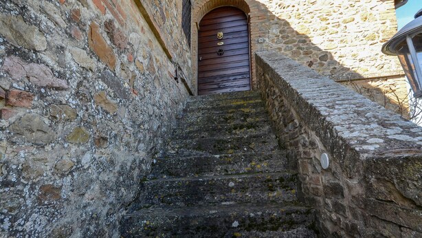 A stone staircase leading to a wooden door with a brass knocker, surrounded by aged stone walls. - La Duchessa Tenuta Donna Olga (Porrona)