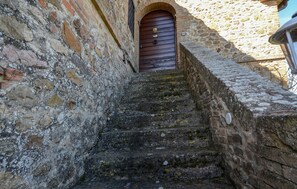 A stone staircase leading to a wooden door with a brass knocker, surrounded by aged stone walls. - La Duchessa Tenuta Donna Olga (Porrona)