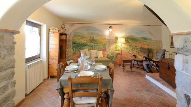 A dining area with a table set for two, a sofa, and a stone fireplace. - Lovely home in Casidore with WiFi (Casidore)