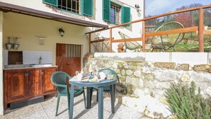 A rustic outdoor kitchen area with a stone wall, a wooden door, and a table with chairs. - Lovely home in Casidore with WiFi (Casidore)