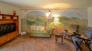 A living room with a sofa, armchairs, a TV, and a mural of a landscape. - Lovely home in Casidore with WiFi (Casidore)