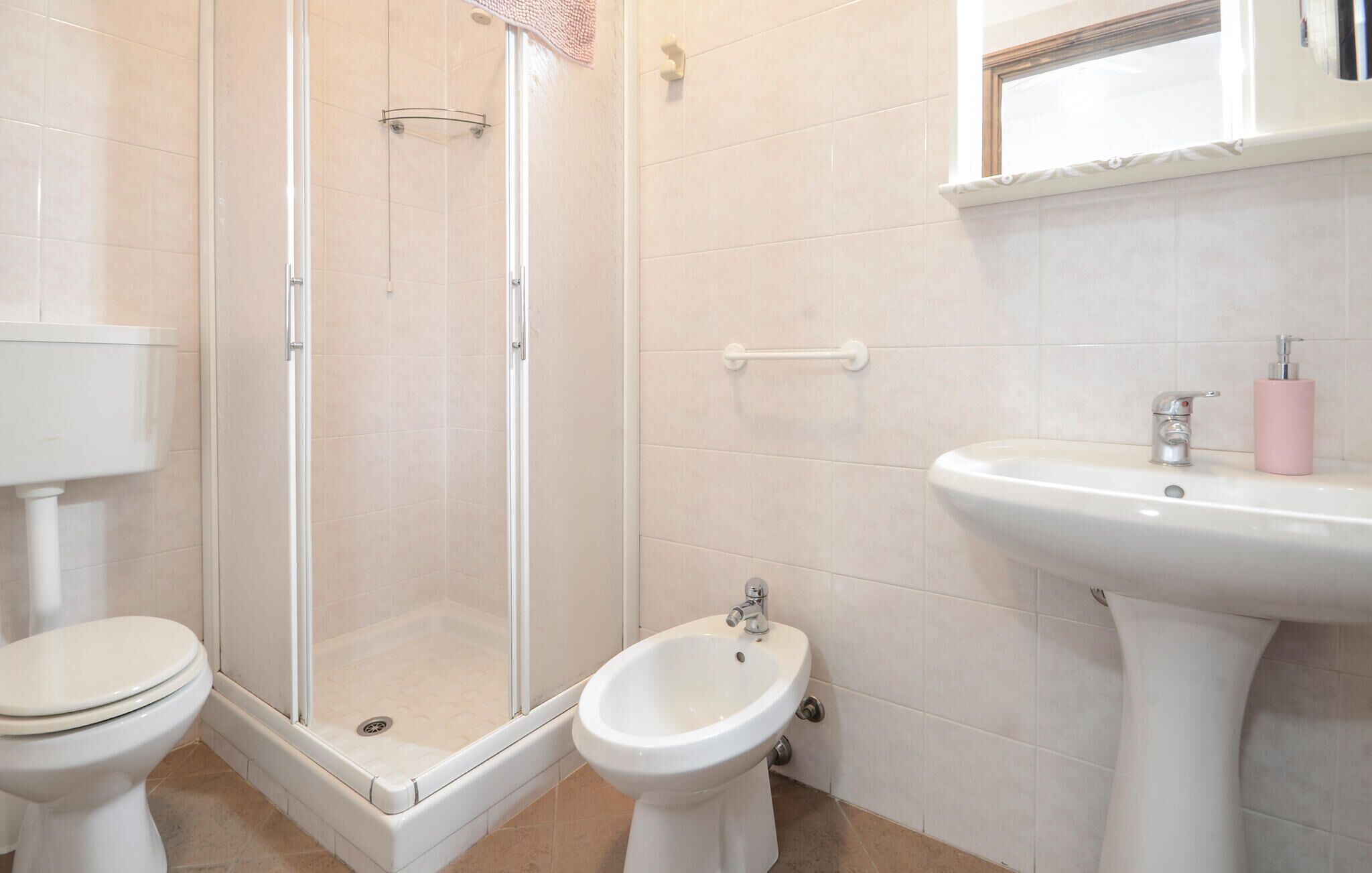 Un baño con inodoro, bidé, ducha y lavamanos.