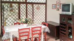 Un espace repas comprenant une table, des chaises, une plante en pot, un téléviseur et un meuble.
