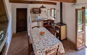A rustic kitchen with a dining table, a stove, and a window. - 1 bedroom stunning home in Anghiari (Anghiari)
