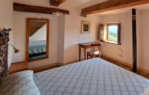 A bedroom with a bed, a wooden ceiling, a window with a view, a desk, and a chair. - 1 bedroom stunning home in Anghiari (Anghiari)